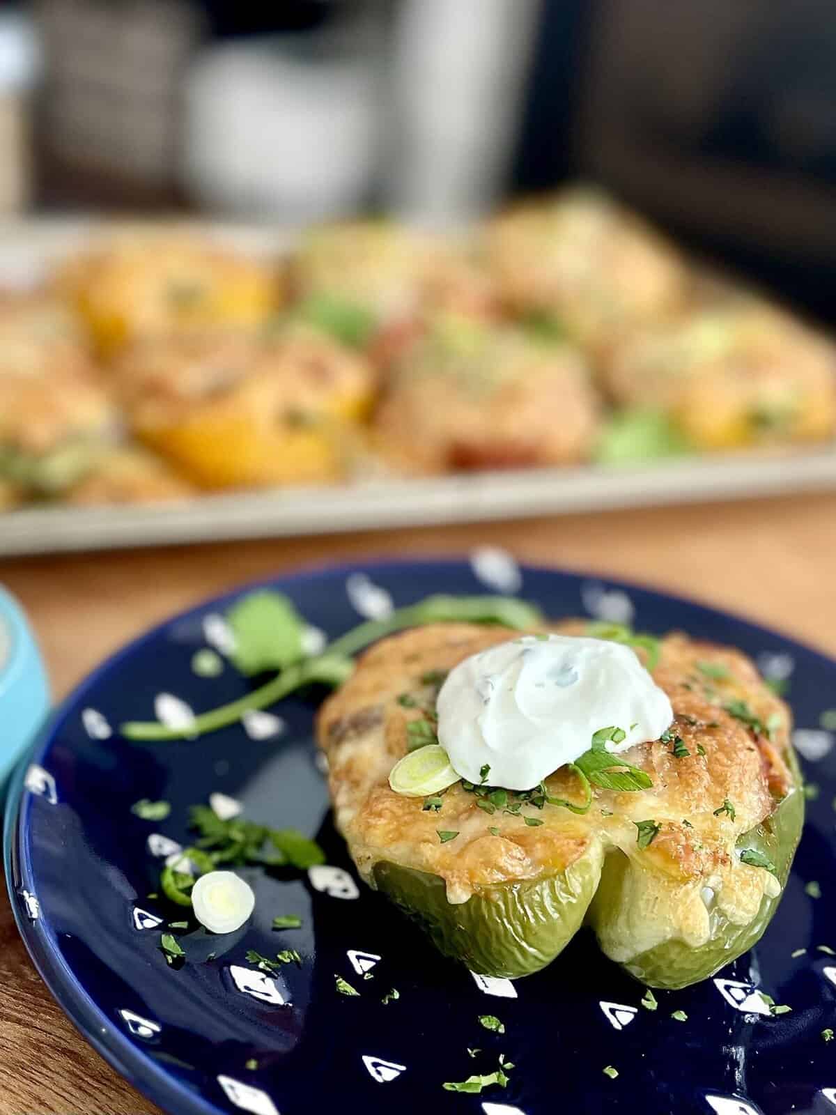 A green chorizo-stuffed pepper topped with melted cheese and a dollop of sour cream