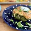 Roasted green bell pepper on a blue plate topped with melted cheese and sour cream
