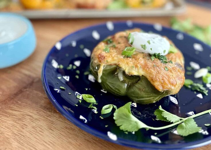 Roasted green bell pepper on a blue plate topped with melted cheese and sour cream