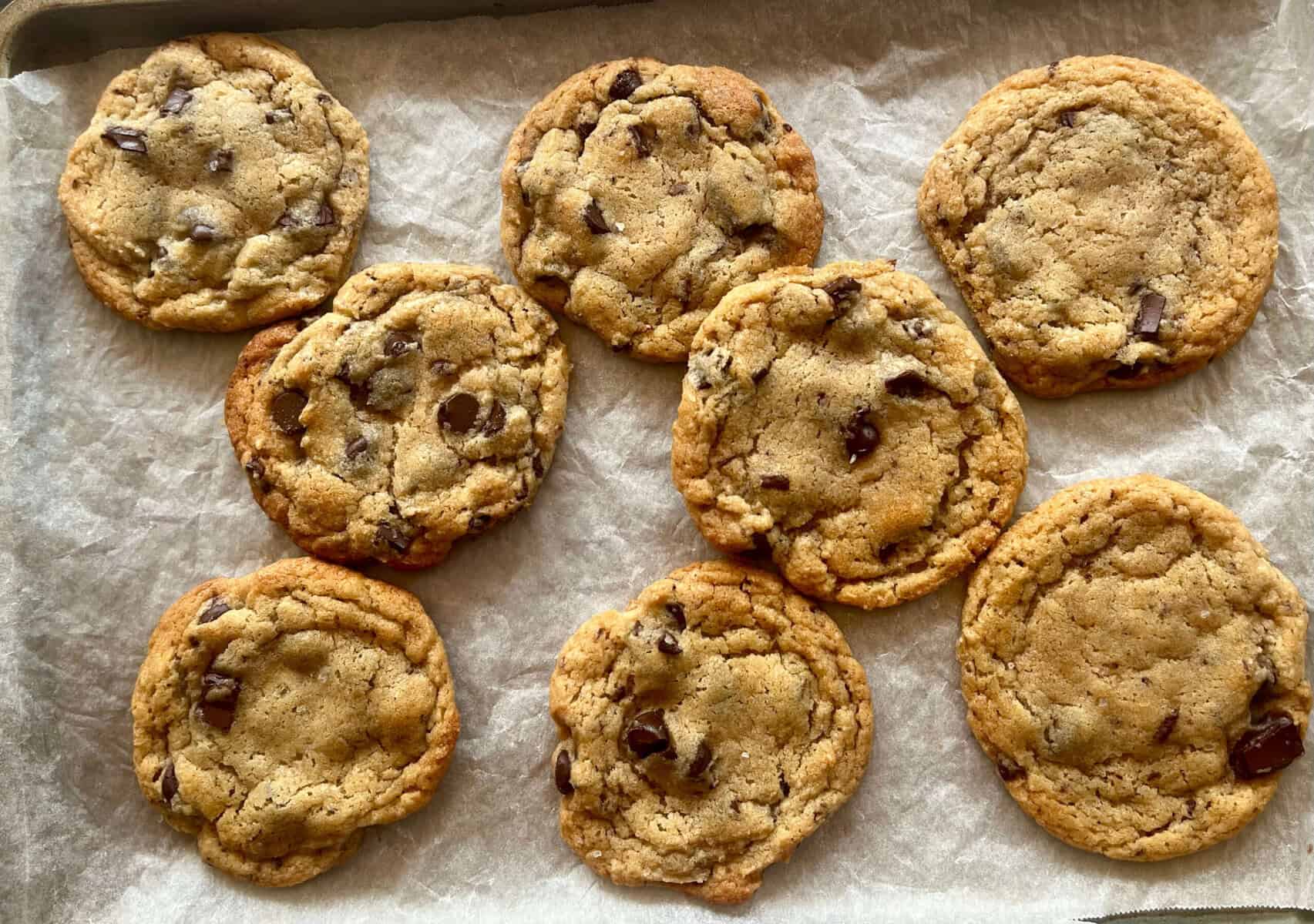 chocolate chip cookies with lightly browned edges on parchment paper